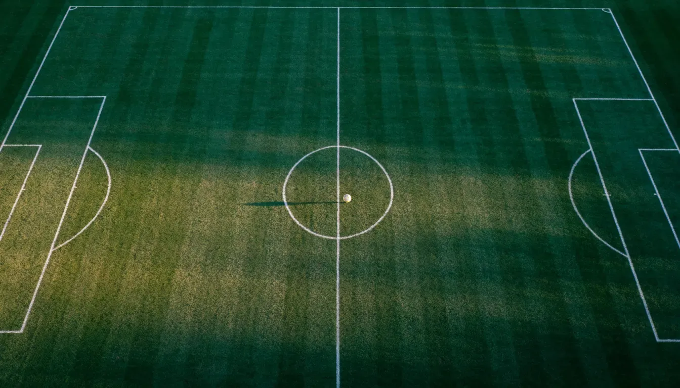 Ein Fussballplatz von oben gesehen, die Linien bilden ein helles Muster auf dem Rasen, Drohnenperspektive in der Morgendämmerung.